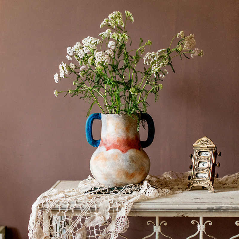Vintage style ceramic vase with wildflowers on lace tablecloth