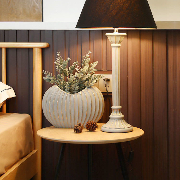 Ceramic oval vase with gold accents on bedside table