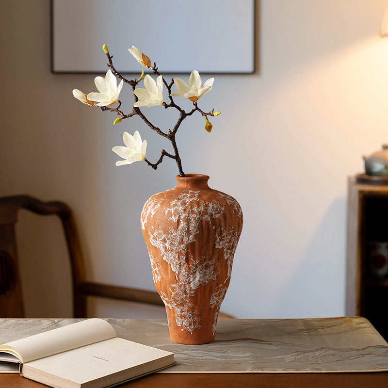 Distressed terracotta ceramic vase with white textured glaze and magnolia flowers