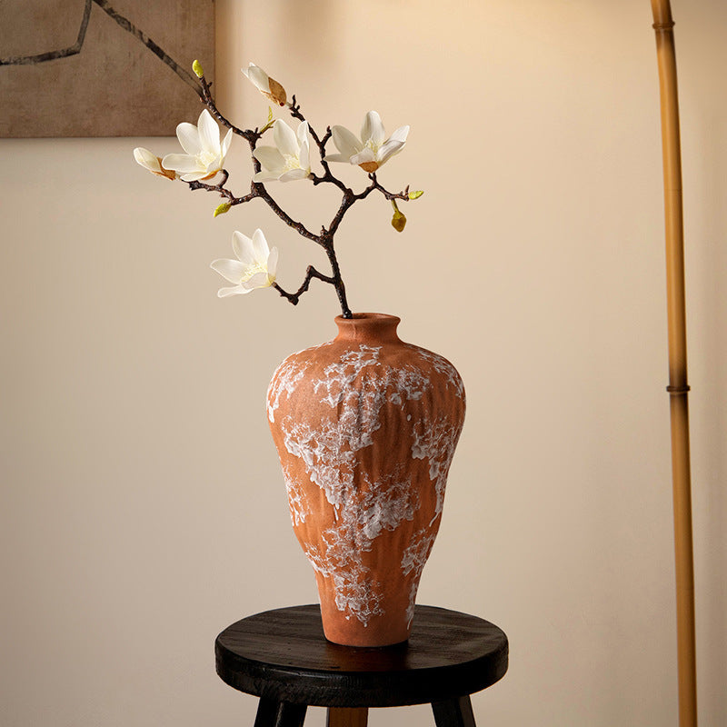 Full view of textured terracotta vase on dark wooden stand