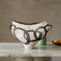 Distressed white and black ceramic centerpiece vase with geometric pattern on wooden table