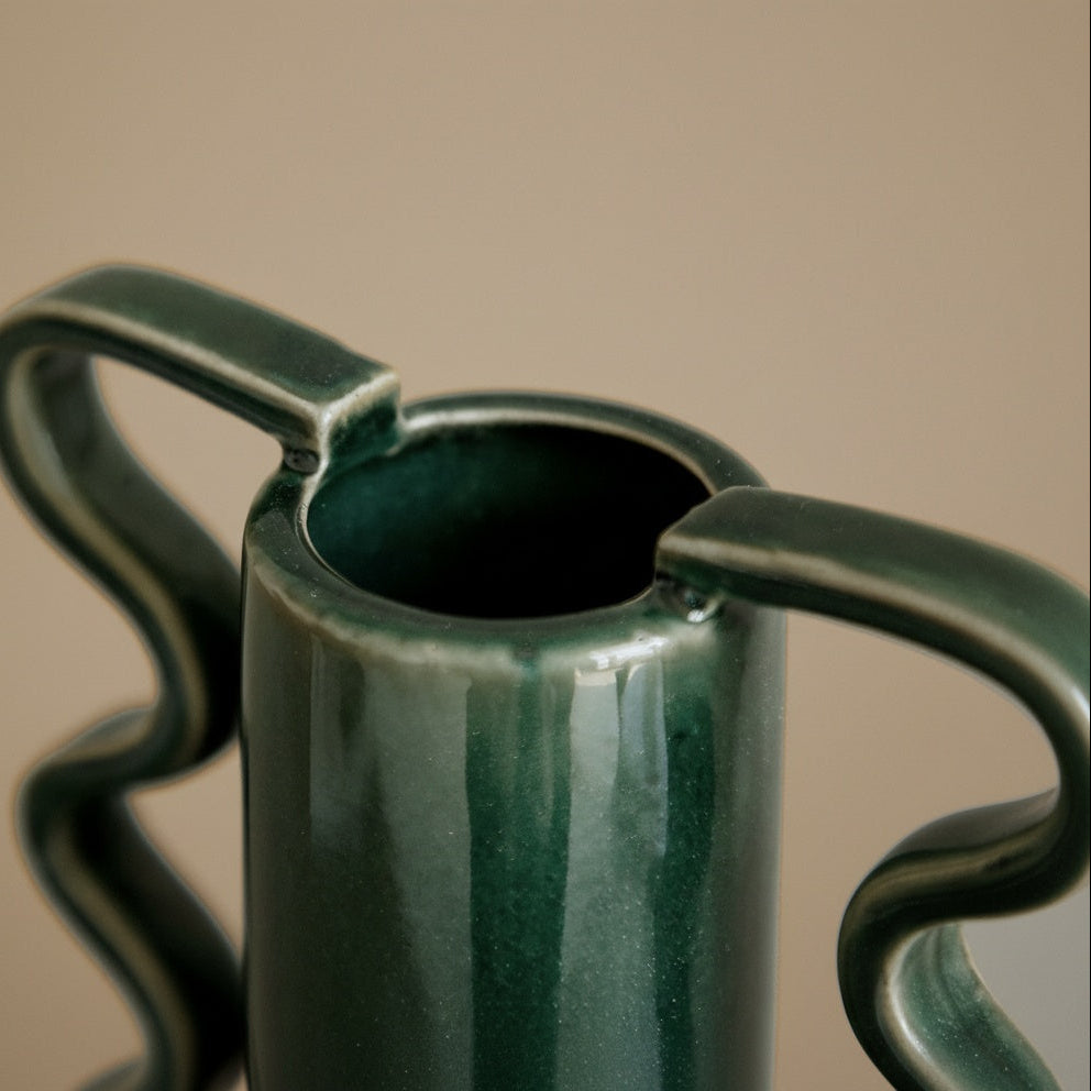 Detail shot of glossy green glaze and wavy handle attachment