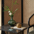 Dark green ceramic vase styled on marble table with white flowers