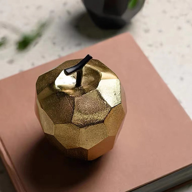 Close up of gold faceted apple sculpture on book