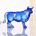 Side view of faceted blue crystal bull figurine on reflective surface