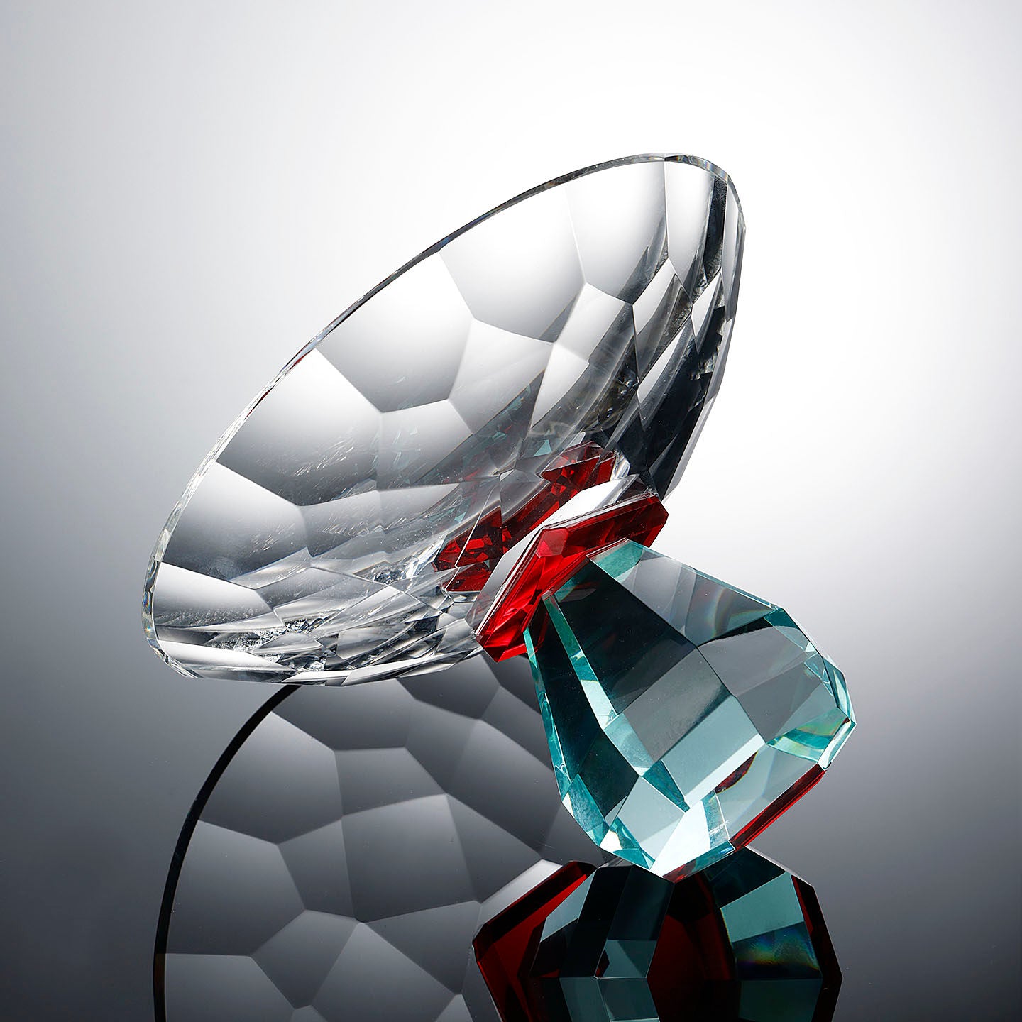 Angled view of faceted crystal pedestal centerpiece bowl with teal geometric base