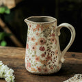 Close up of floral patterned ceramic pitcher vase on wooden table