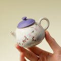 Hand holding the miniature floral ceramic teapot