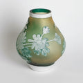Front view of frosted green and amber glass vase with white floral relief