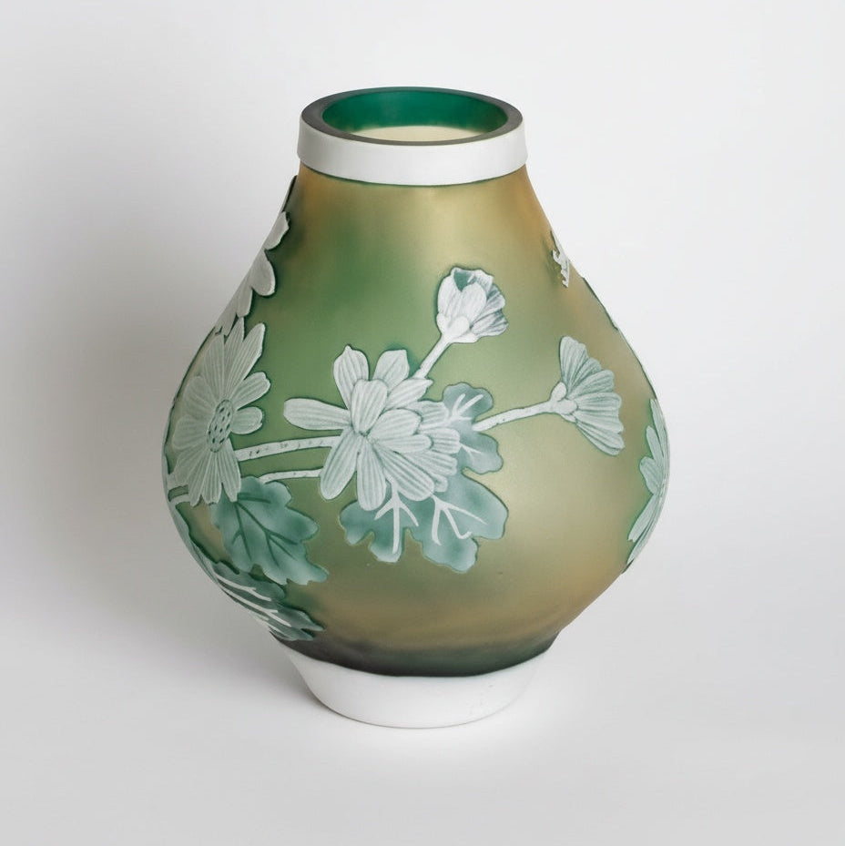 Front view of frosted green and amber glass vase with white floral relief