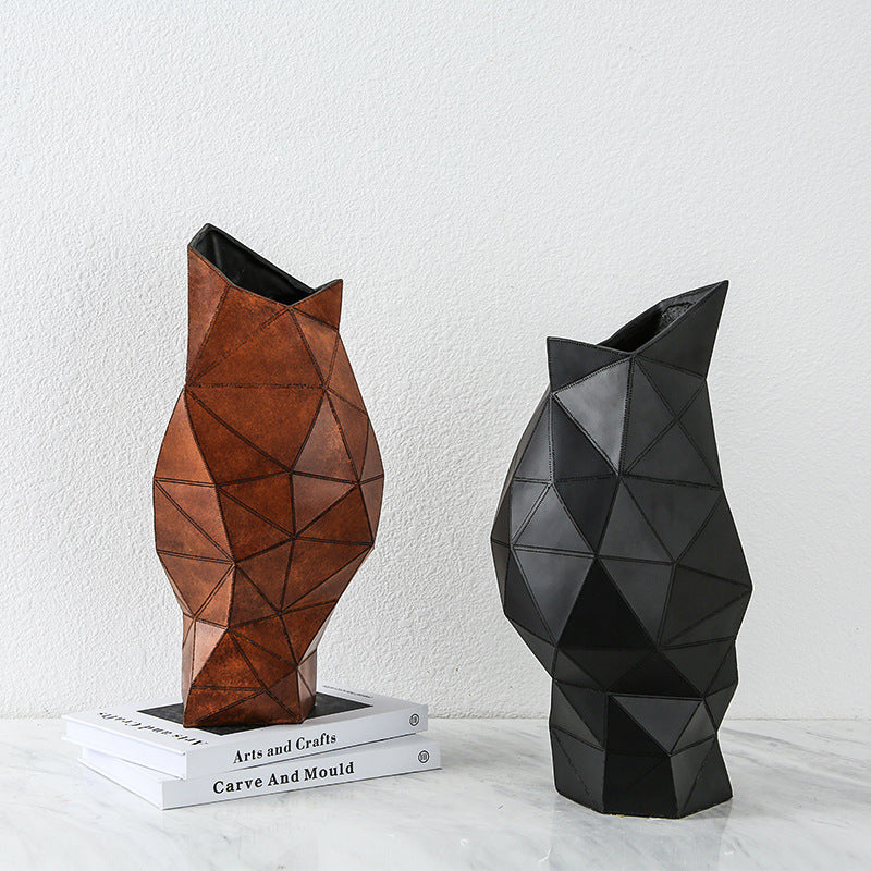 Geometric faceted resin vases in brown and black on marble surface