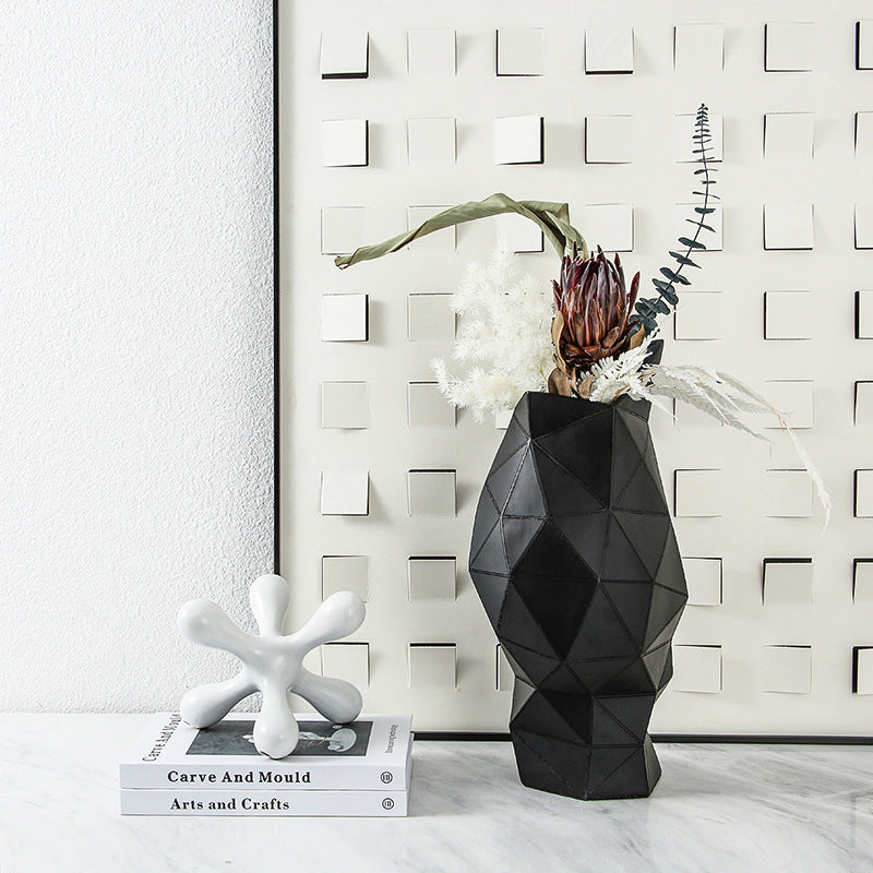 Black geometric faceted vase styled with dried florals against wall art