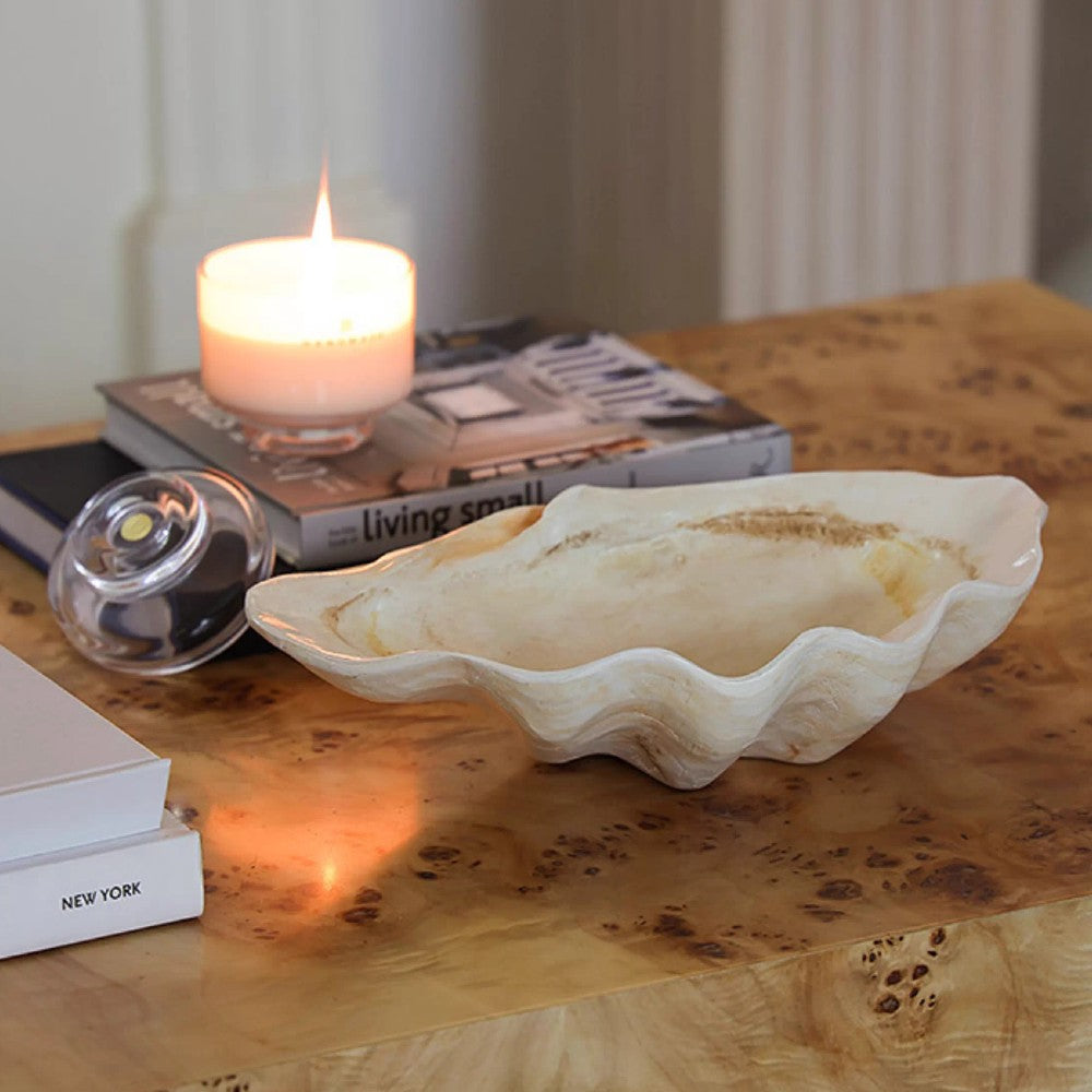 Shell-inspired decorative resin bowl styled on a table with candle and glass decor
