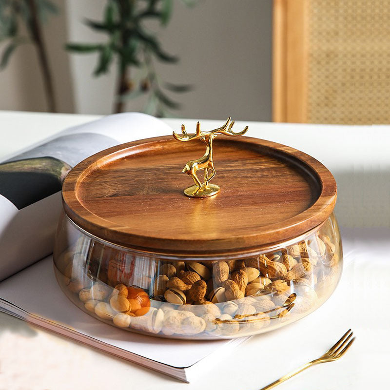 Front view of glass serving bowl with wood lid and gold deer handle on table