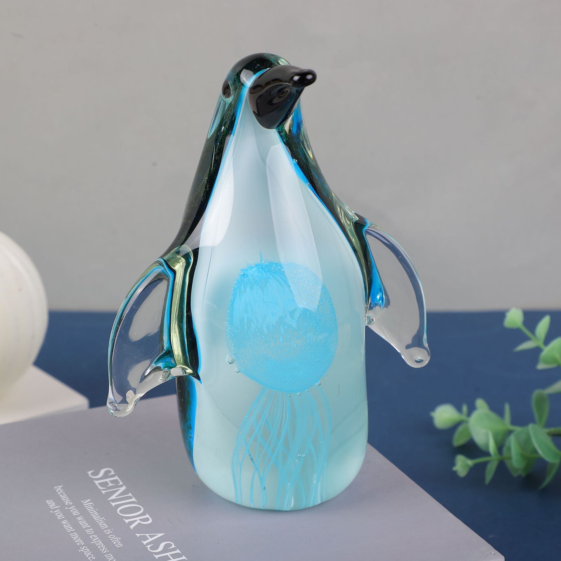 Lifestyle shot of glass penguin paperweight on a book