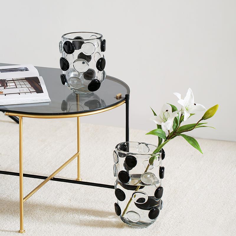 Close up of large glass vase with flowers on carpet