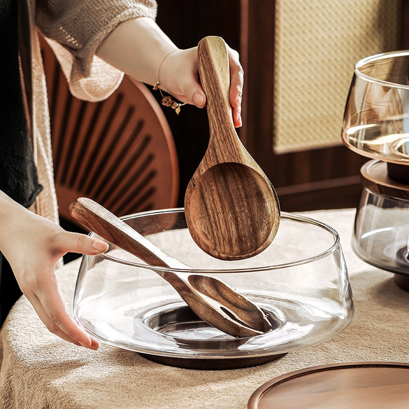 Empty clear glass serving bowl with wooden spoon