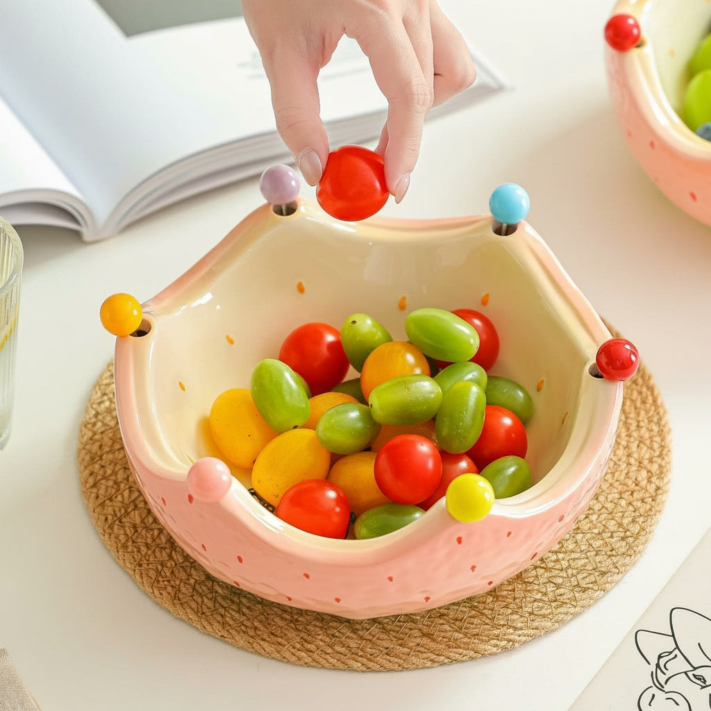 Hand placing a cherry tomato into the glazed ceramic crown fruit bowl