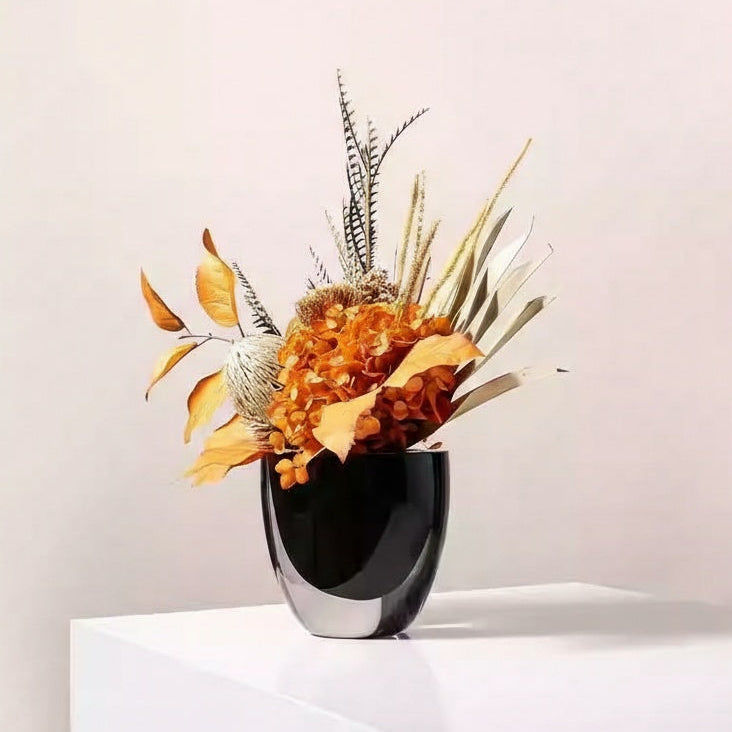 Angled view of black and clear glass vase on white surface