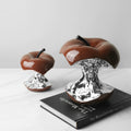 Glossy brown apple sculpture with silver chrome core styled on design book