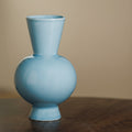 Light blue glossy ceramic vase with spherical body detail