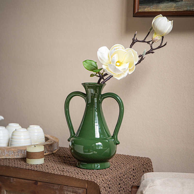 Glossy green ceramic amphora vase with magnolia flowers