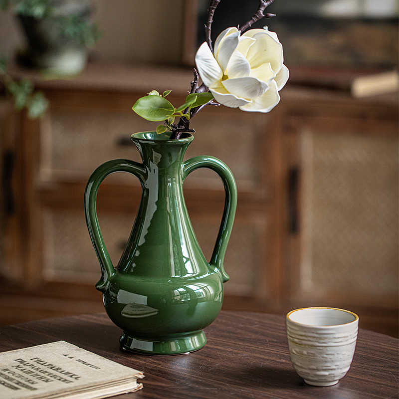 Side view of green ceramic dual handle vase on table