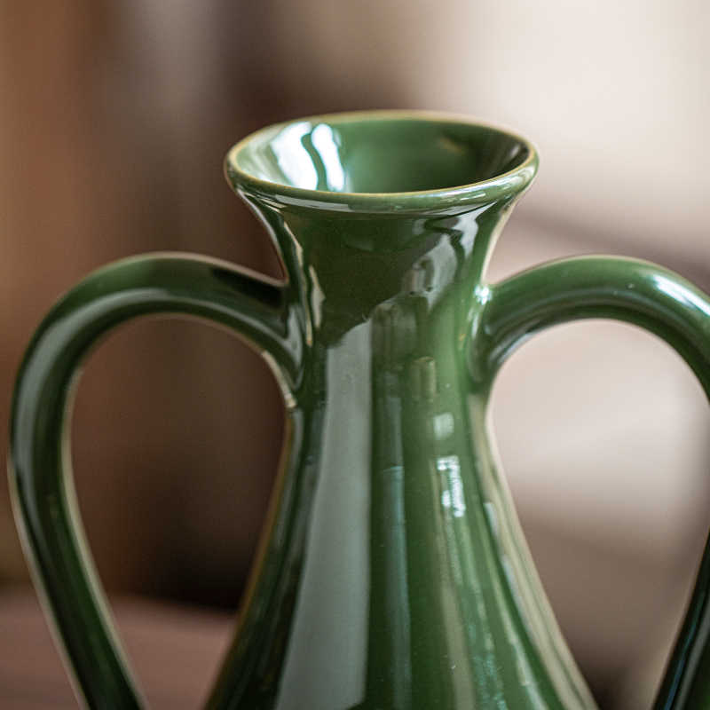 Close up detail of green ceramic vase neck and handle