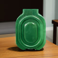 Front view of green ceramic geometric vase on wooden table