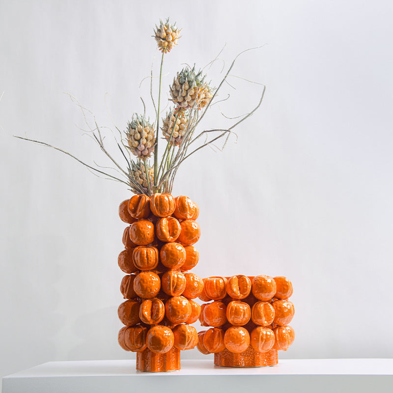 Group shot of tall orange bubble vase and wide planter with floral arrangement