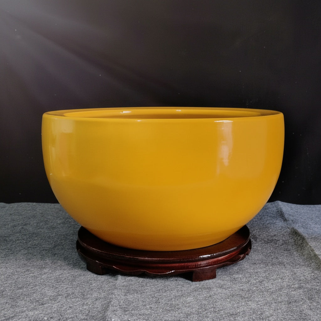 Glossy yellow ceramic decorative bowl on wooden stand