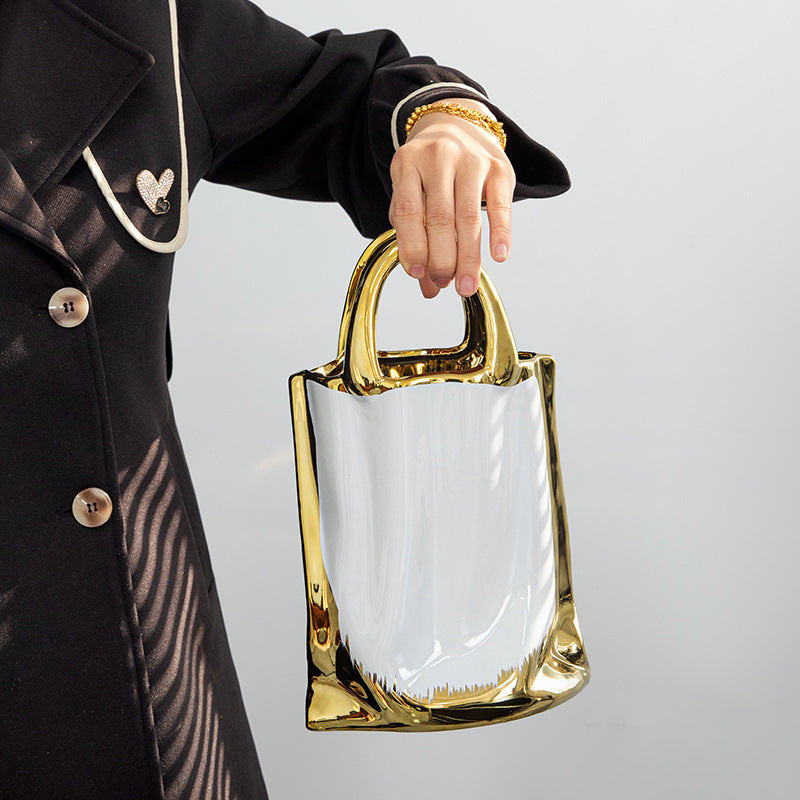 Hand holding gold handle of ceramic bag vase