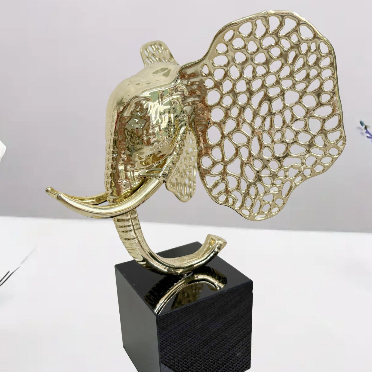 Angled view of gold elephant sculpture on black base