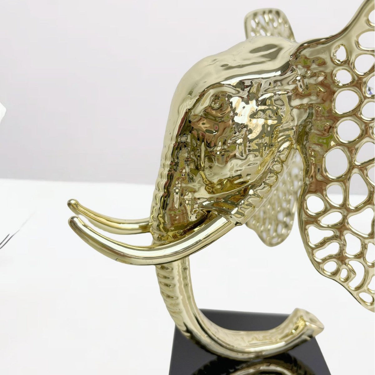 Close up detail of textured gold elephant face and lattice ear design