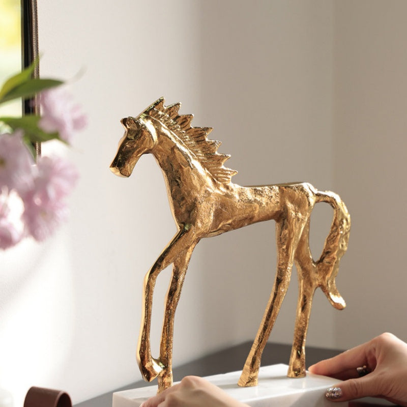 Gold finished aluminum horse sculpture on white marble base side view