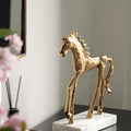 Front angle view of textured gold horse statue on marble