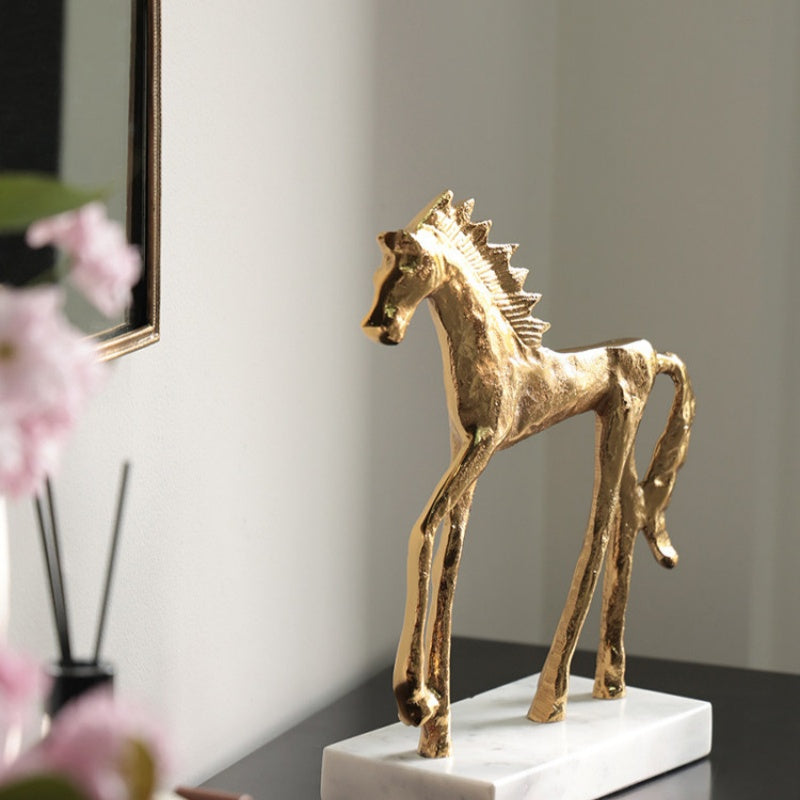Front angle view of textured gold horse statue on marble