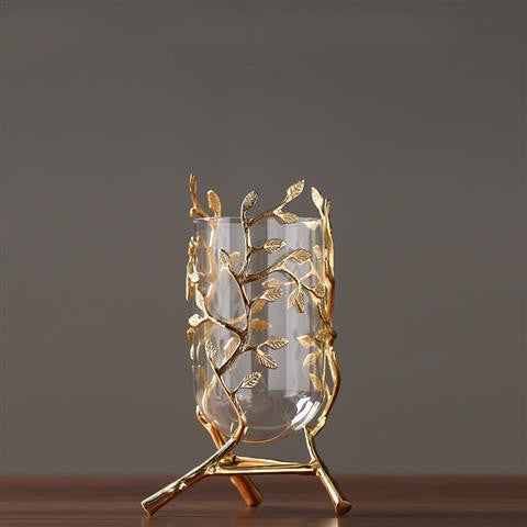 Empty glass vase held by gold leaf metal structure
