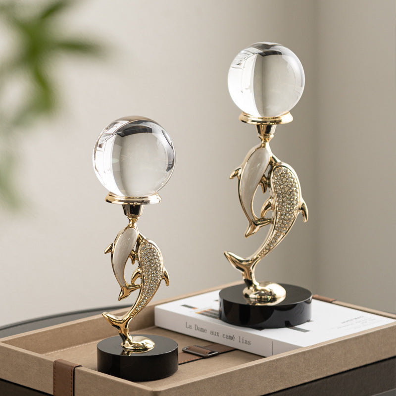 Twin gold dolphins holding crystal sphere on black base