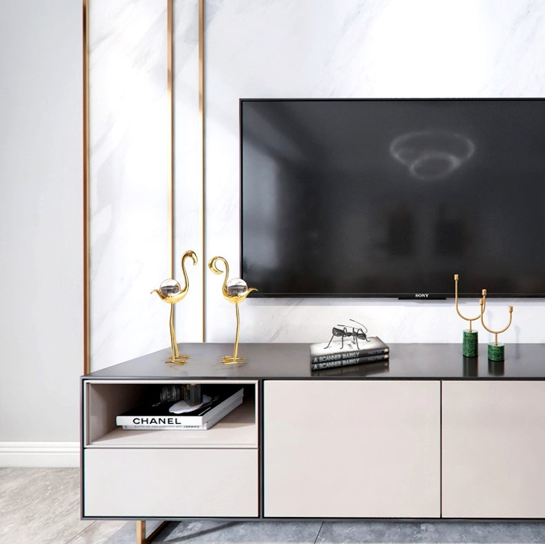 Lifestyle setting showing gold flamingo figurines on a media console