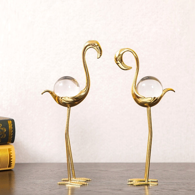 Close up of gold and crystal flamingo figurines on a dark surface