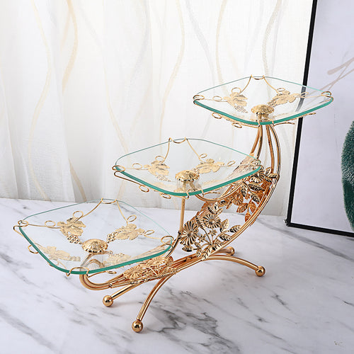 Angled view of gold and glass 3-tier serving stand with floral details