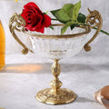Gold-finished pedestal bowl with glass vessel and ornate handles front view