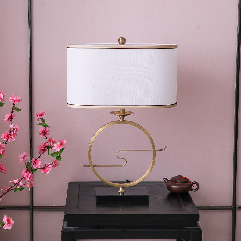 Front view of gold iron circle table lamp on black table