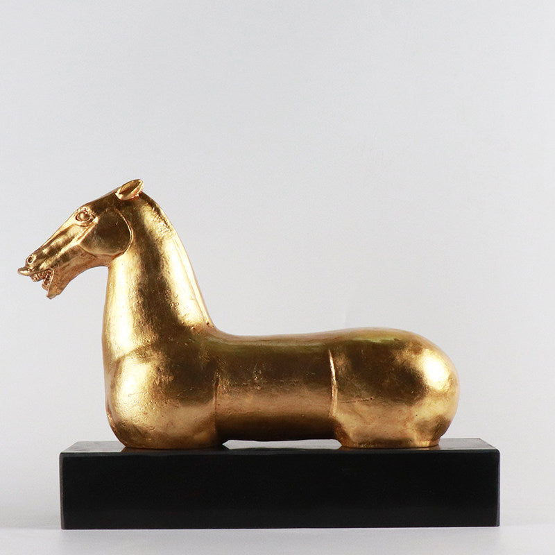 Side view of gold horse sculpture on black base