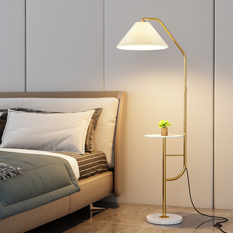 Gold metal arched floor lamp with integrated table in bedroom setting