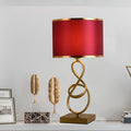 Gold metal twisted loop table lamp with red shade front view