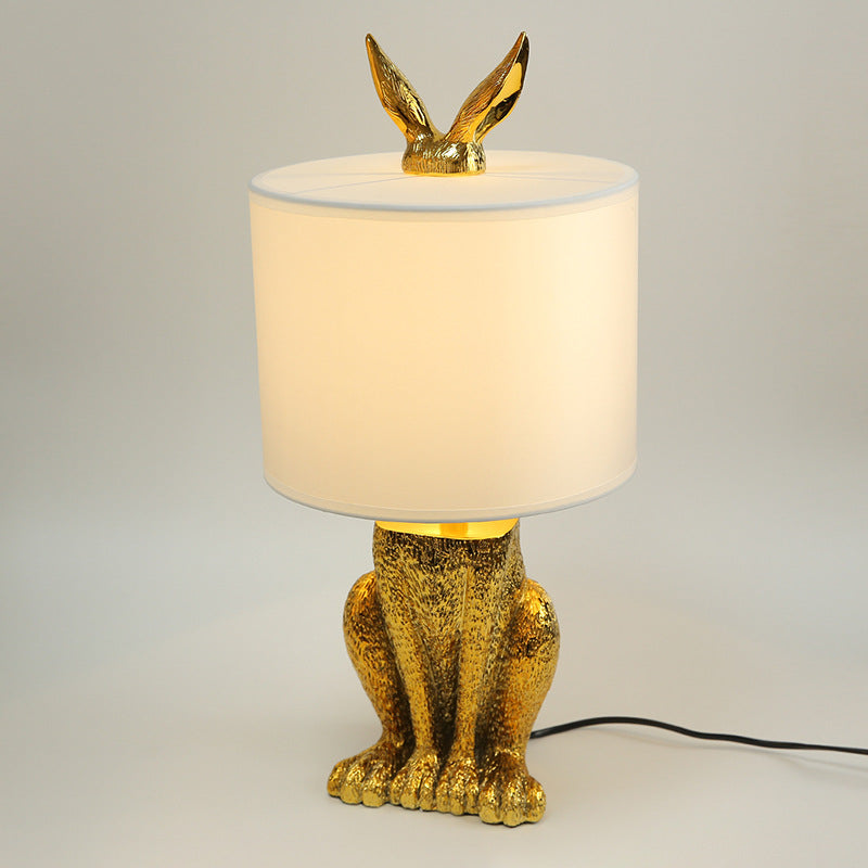 Front view of gold rabbit lamp with ears poking through shade