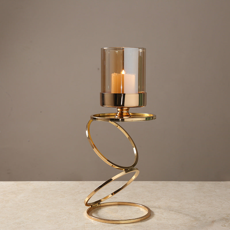 Gold metal spiral candle holder with lit candle and glass shade front view