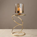 Large gold helix candle stand with glass cylinder on beige surface